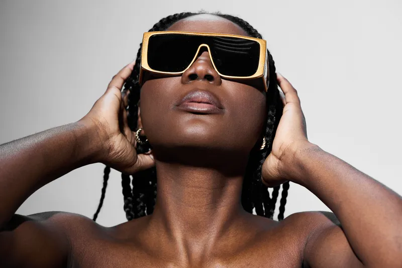 Confident woman in oversized sunglasses, showcasing beauty and elegance in a minimalist setting, perfect for fashion and lifestyle concepts