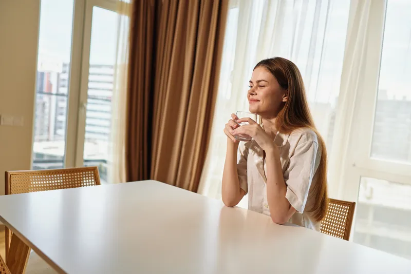 Woman mug coffee morning table window sunlight relaxation at home, sitting with a mug by the window, enjoying aroma and peaceful cozy moment in bright daylight.