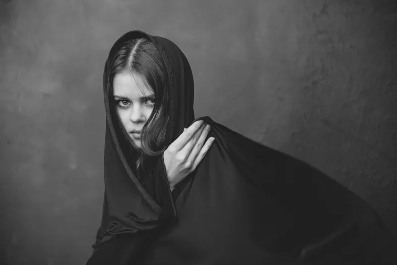 Черно-белая фотография молодой женщины с тканью на голове, кадрированный крупный план