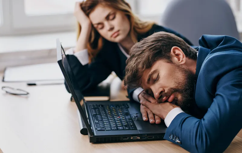 Коллеги по работе спят за столом перед ноутбуком, усталость, отдых