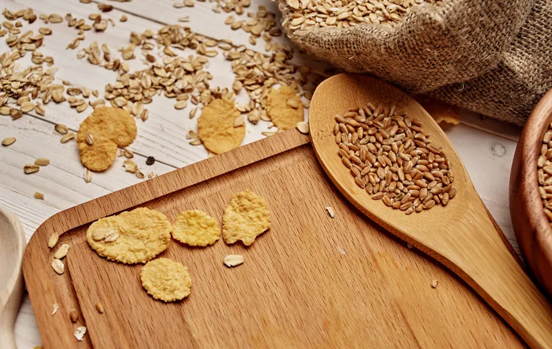 Цельнозерновые крупы и злаки на деревянной доске, приготовление еды на столе