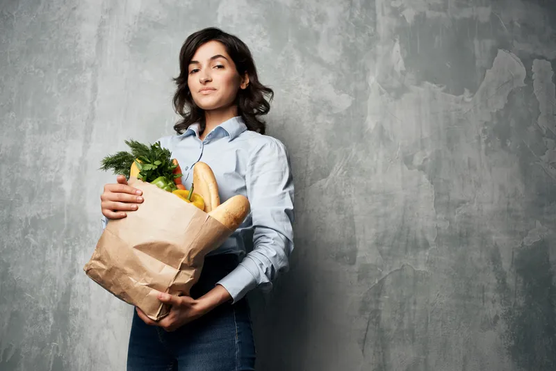 Улыбающаяся брюнетка с пакетом продуктов в супермаркете, овощи, еда, диета