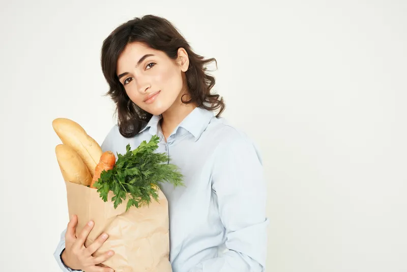 Улыбающаяся женщина с пакетом продуктов, здоровая еда в супермаркете, домохозяйка