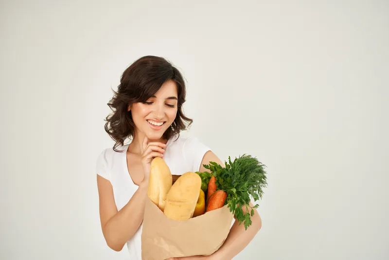 Симпатичная женщина с пакетом продуктов из супермаркета