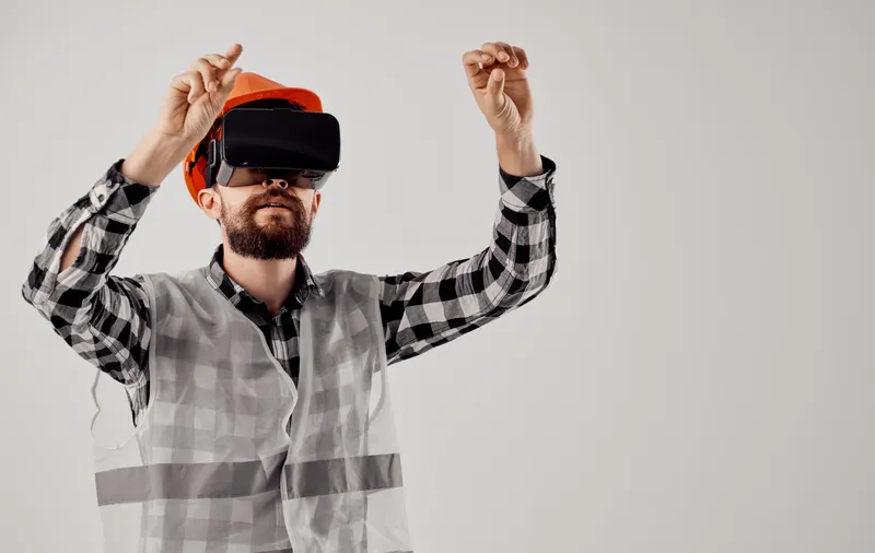 Инженер-строитель в оранжевой каске и 3D-очках на светлом фоне