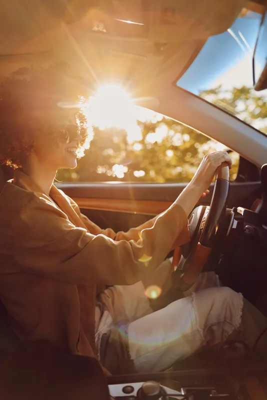 Senior driver sits behind the wheel during a warm sunset, cabin lit by golden light, calm everyday travel moment, lifestyle scene with nostalgic retro mood.