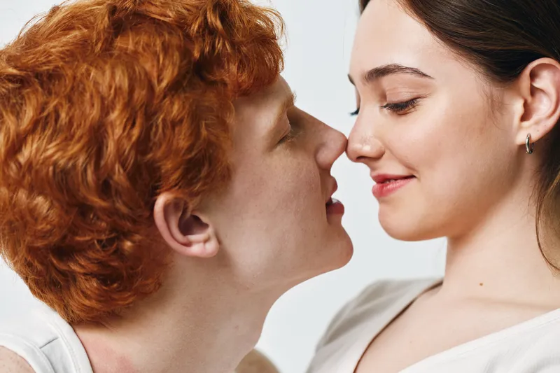 Couple, young man and woman facing each other with closed eyes and gentle smile in intimate moment. Romance, love, emotion and tenderness captured on white background.