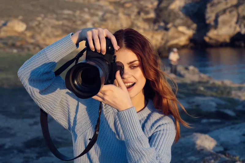 Веселая женщина-фотограф на фоне скалистых гор, пейзаж, отдых на природе