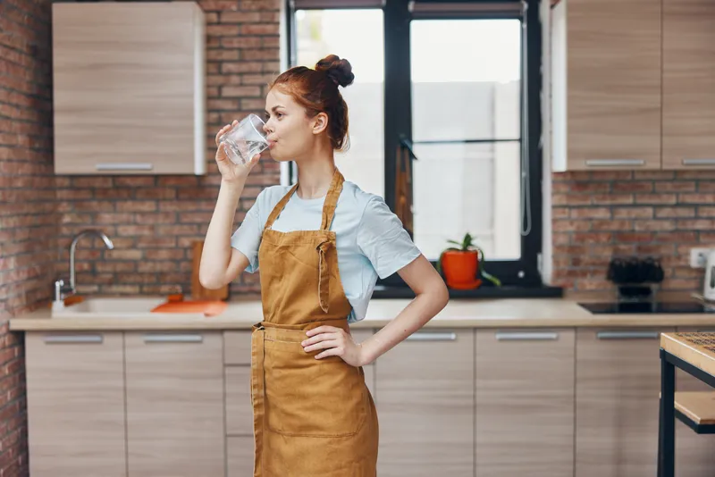 Симпатичная женщина пьет воду на кухне