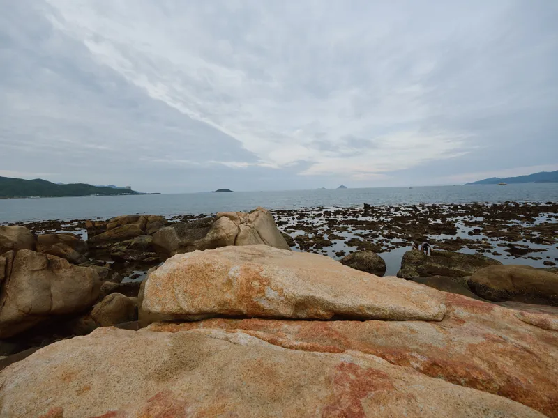 Tranquil coastal scenery featuring smooth rocks and ocean under a cloudy sky, ideal for relaxation and nature themed projects