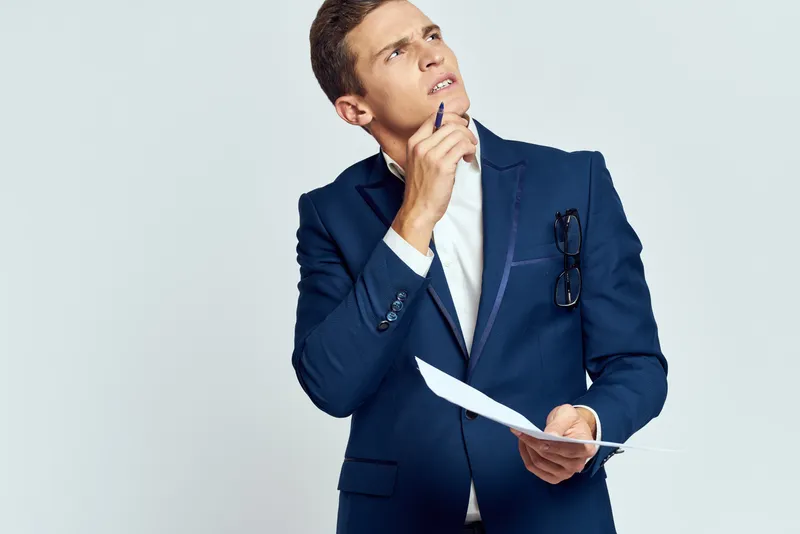 Деловой мужчина в пиджаке с документами в руках на светлом фоне, работа, заинтересованный взгляд
