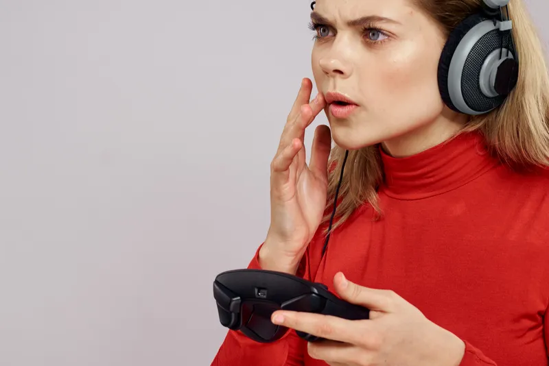 Женщина в наушниках с джойстиком в руках играет в игры