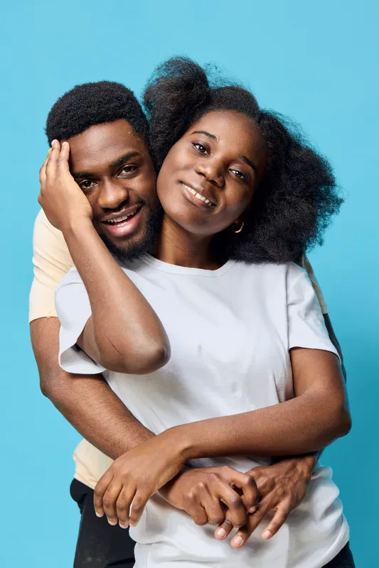 Loving couple embracing against a bright blue background, showcasing joy and intimacy in a contemporary setting, perfect for celebrating relationships and diversity
