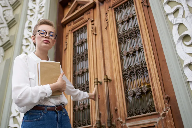 Коротко стриженная женщина с книгой в руках на открытом воздухе, читает, общается