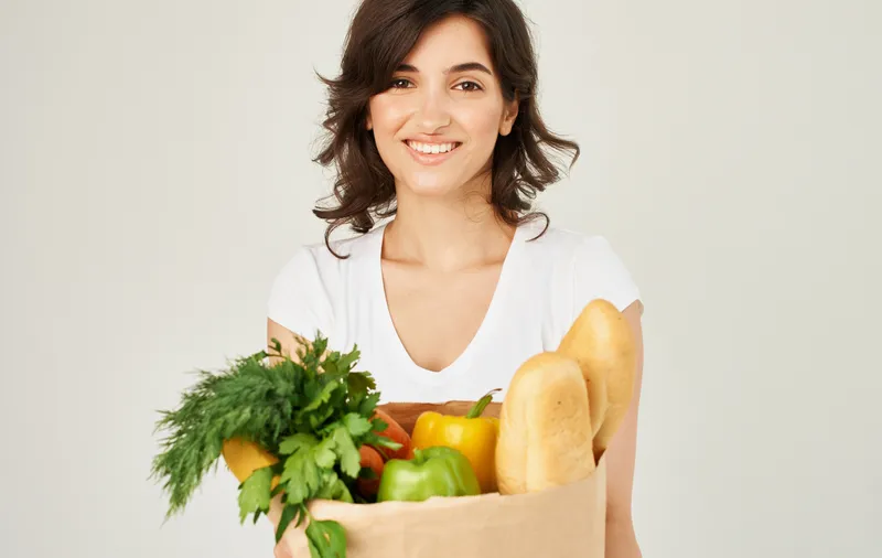 Веселая женщина с пакетом здоровой еды, свежие продукты