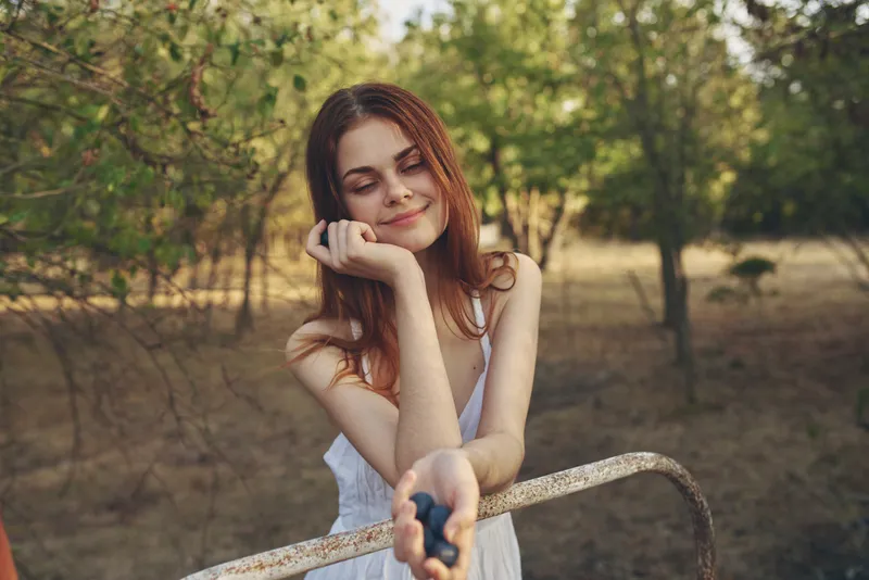 Крупный план женщины в белом платье, которая ест виноград