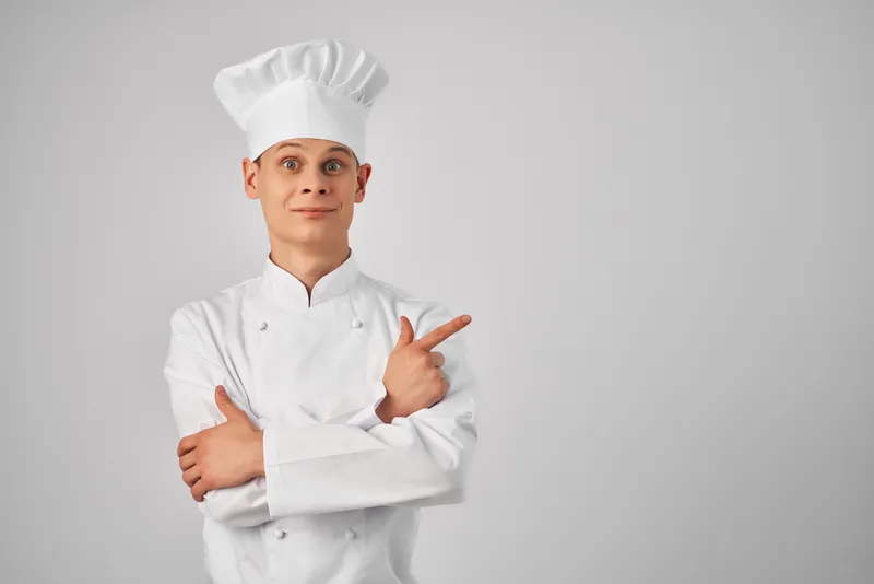 Весёлый шеф-повар-мужчина жестикулирует руками на кухне ресторана