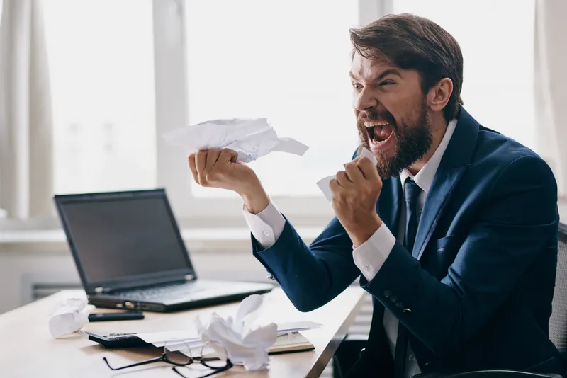 Бизнесмены работают за ноутбуком в офисе, на их лицах недовольство, вокруг технологии