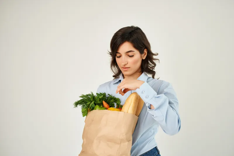 Жизнерадостная женщина с пакетом продуктов в супермаркете, здоровое питание, овощи