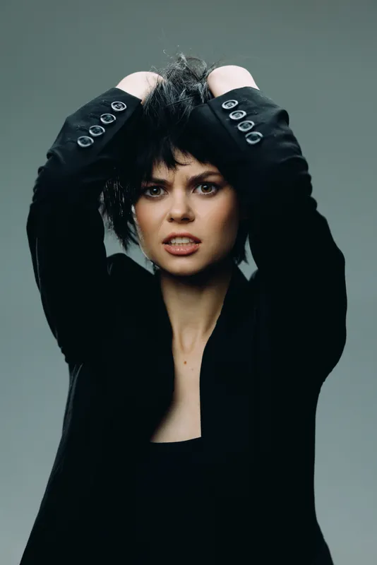 frustrated woman with short black hair in black suit jacket expressing tension and stress