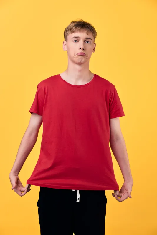 Young male red shirt casual fashion expressive pose bright background in a studio setting conveying confident style and relaxed energy with bold presence