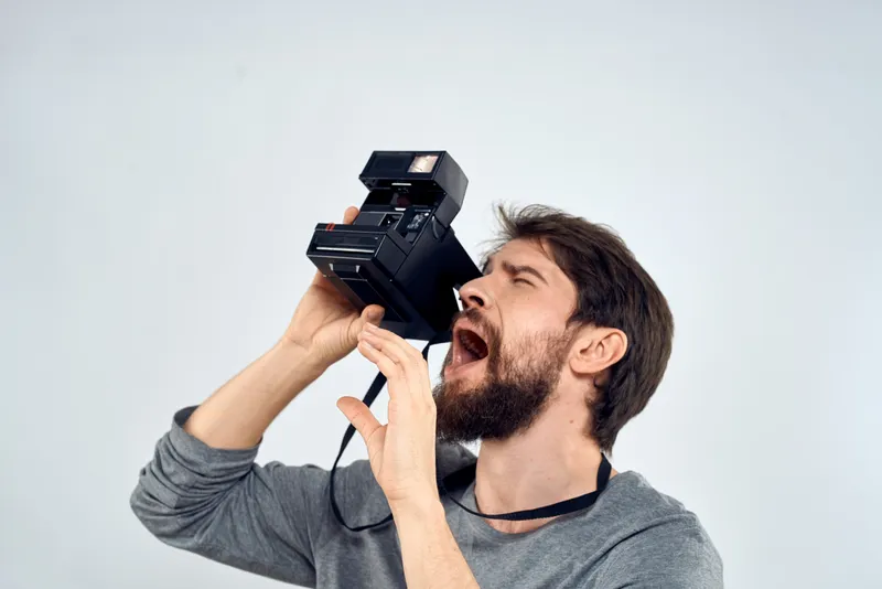 Мужчина-фотограф с профессиональной камерой, работа в студии, современные технологии, искусство, светлый фон