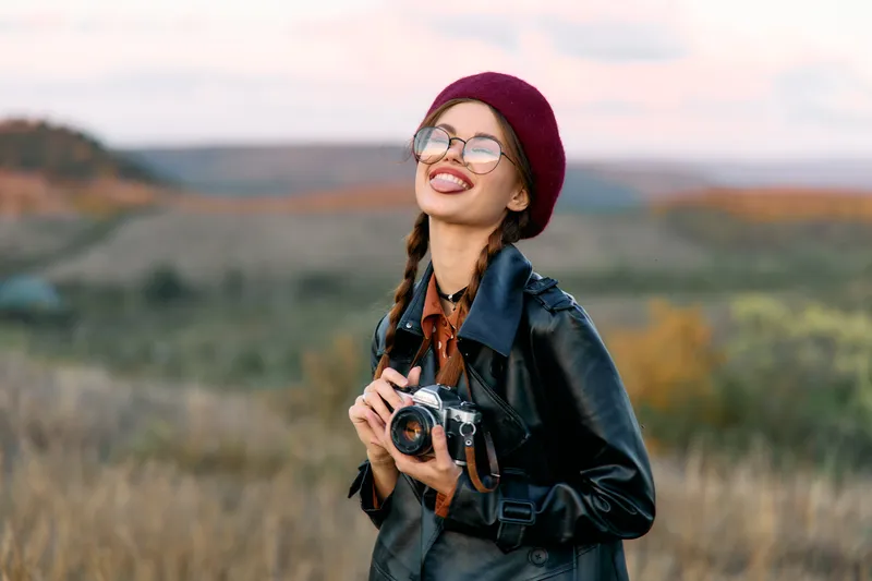 Фотограф в шляпе и солнцезащитных очках делает снимки в залитом солнцем поле, запечатлевая яркую красоту природы