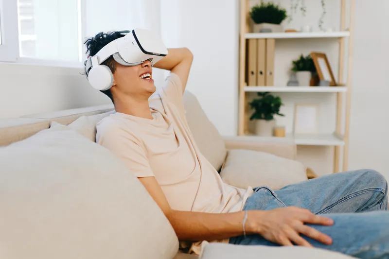 Молодой человек погружён в опыт виртуальной реальности: на нём VR-шлем и наушники