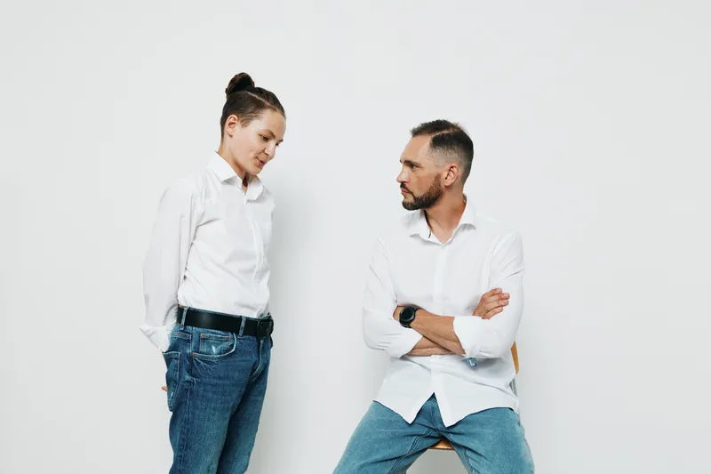 A professional man stands with a colleague in a business setting, against an isolated colored background. They project focus, confidence, and calm during a strategic discussion about goals.