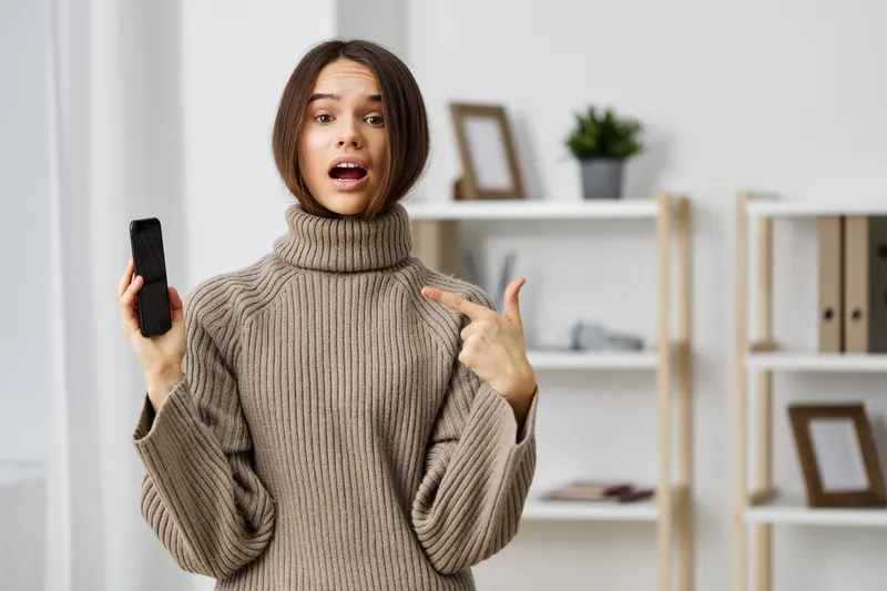 Женщина сидит на диване и делает селфи на смартфон