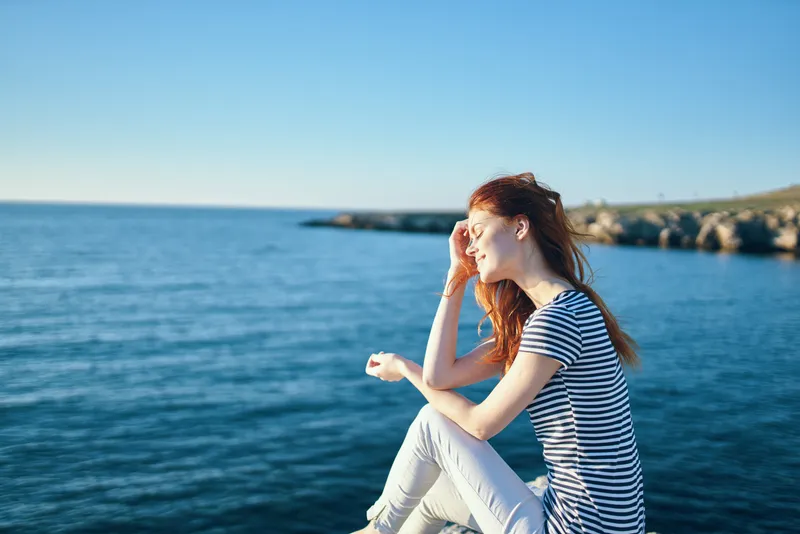 Женщина на скале у моря в горах, закат, лето