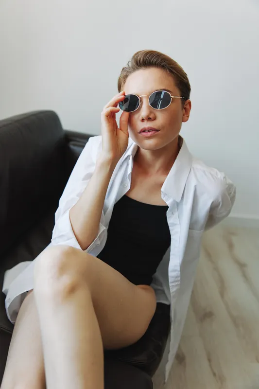 Женщина лежит на диване в очках и извивается