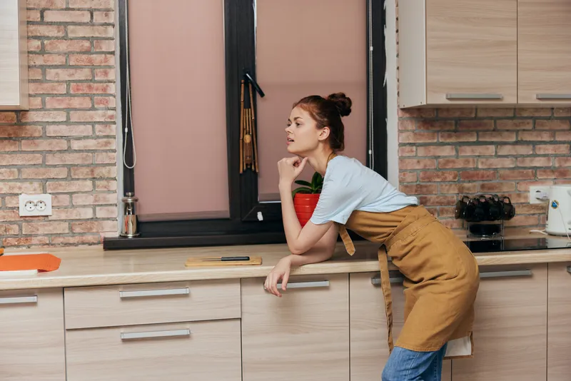 Жизнерадостная женщина на кухне в квартире, среди кухонной утвари и предметов интерьера, домашняя жизнь