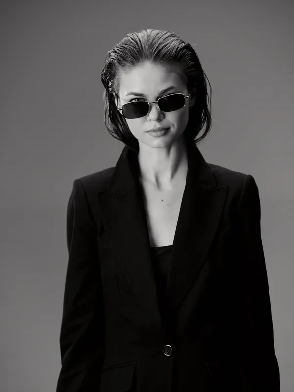 Black and white portrait of a woman wearing sunglasses and a black blazer with confident expression
