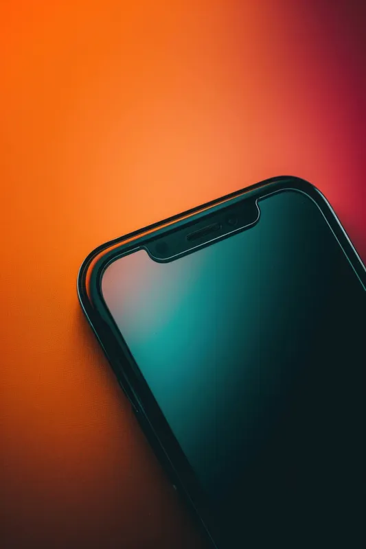 Стильный смартфон с дисплеем от края до края, лежащий на красочном градиентном фоне, символизирующий современные технологии и эстетику дизайна
