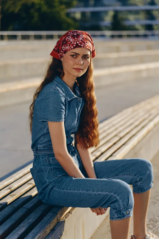 lifestyle woman in modern boho-western denim street style with a red bandana, relaxed pose and natural light capturing film color tones and casual urban vibe