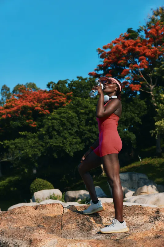 Спортивная женщина наслаждается водой на природе, демонстрируя физическую форму и здоровье, на фоне красочной листвы