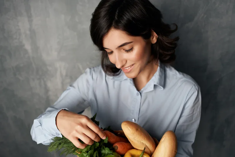 Симпатичная женщина с пакетом овощных продуктов: здоровая пища, диета