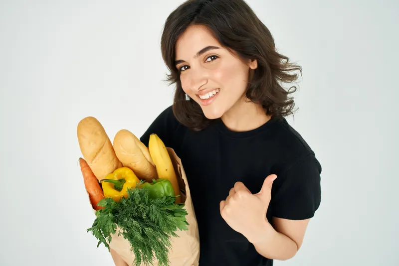 Женщина с пакетом продуктов совершает покупки здоровой еды в супермаркете