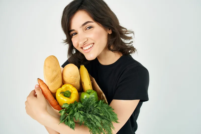 Весёлая женщина с пакетом продуктов и овощей, что символизирует доставку