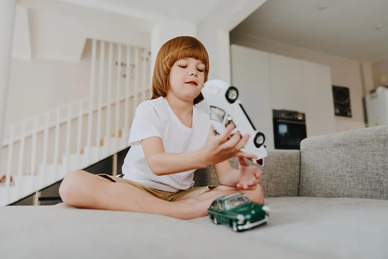 Engaging boy playing with toy cars in a cozy living room, showcasing creativity and imagination. A bright and cheerful scene of childhood joy and exploration.