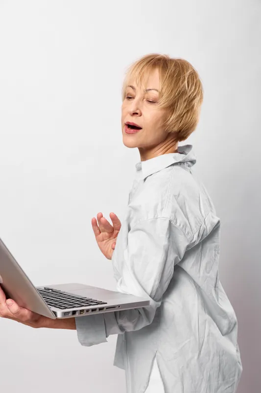 Senior woman doctor using laptop for telemedicine consultation, online communication, close up on white studio background, calm focused expression, healthcare support