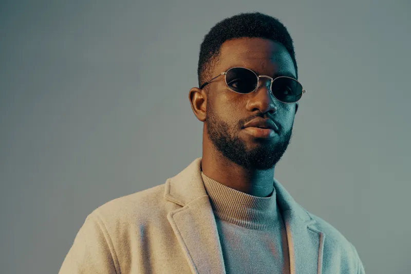 Stylish young man with sunglasses in a light colored outfit, exuding confidence and modern elegance, perfect for lifestyle and fashion photography