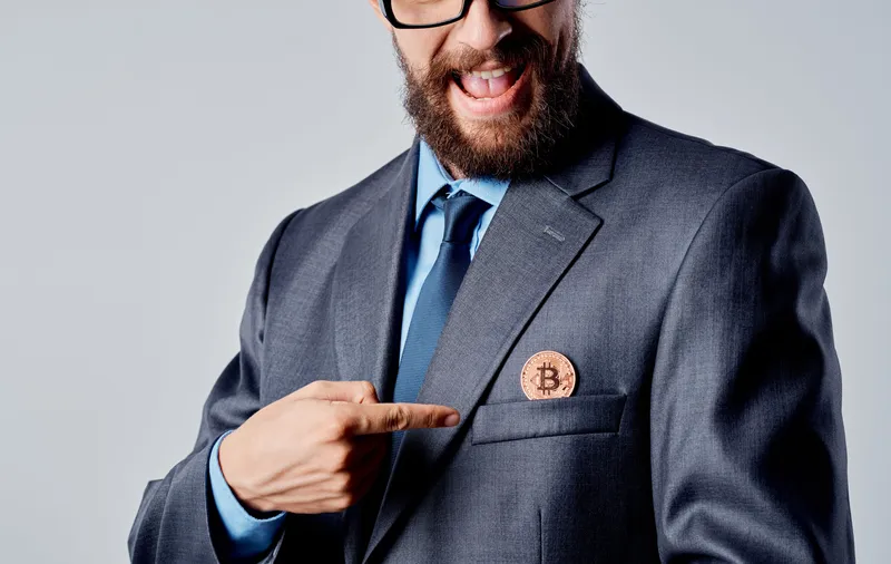 Мужчина держит золотые монеты криптовалюты Bitcoin на фоне курса доллара
