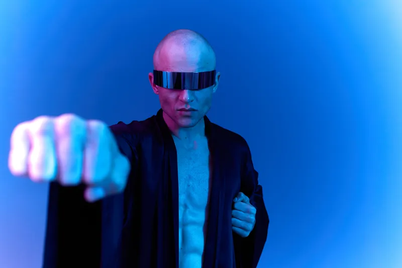 Futuristic man in dark robe, showcasing an imaginative blend of technology and fashion with striking blue tones. Captivating composition in a unique style.