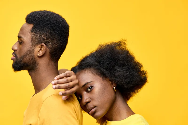 Young couple in vibrant yellow attire against a bright yellow background, showcasing love and connection, emphasizing emotional intimacy and cultural representation