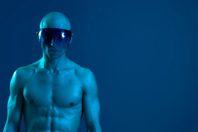 A muscular man with a futuristic visor, showcasing a vibrant blue skin tone. The image presents a striking, monochromatic color scheme, emphasizing a sci-fi concept.