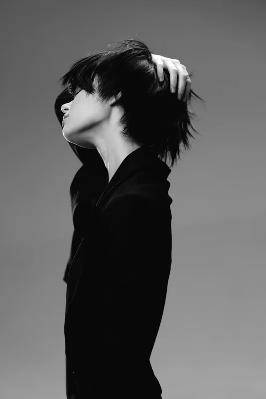 Black and white profile of a woman with short hair touching her head in a minimalist style.