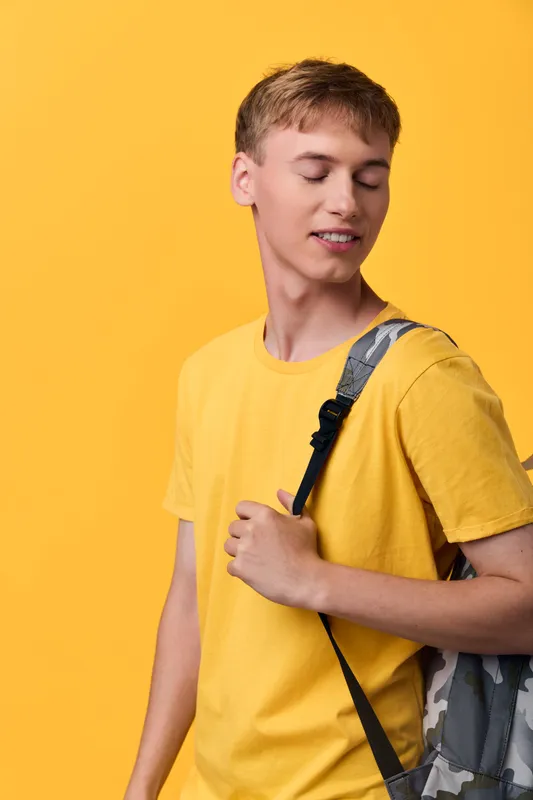 Teen, boy, backpack, yellow, casual, youth, fashion, accessory, relaxed pose against a bright backdrop, showcasing everyday style and confident, youthful energy.