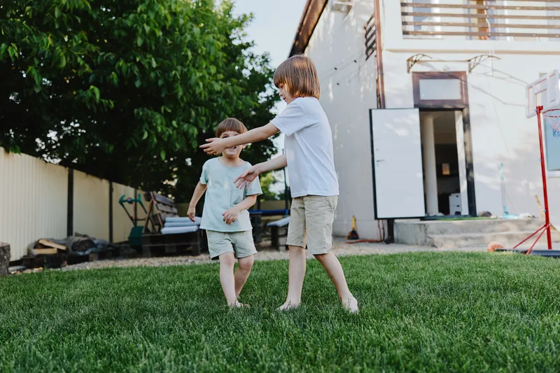 Playful boys enjoying a sunny day in the garden, surrounded by greenery and laughter, capturing the essence of childhood happiness and outdoor fun.